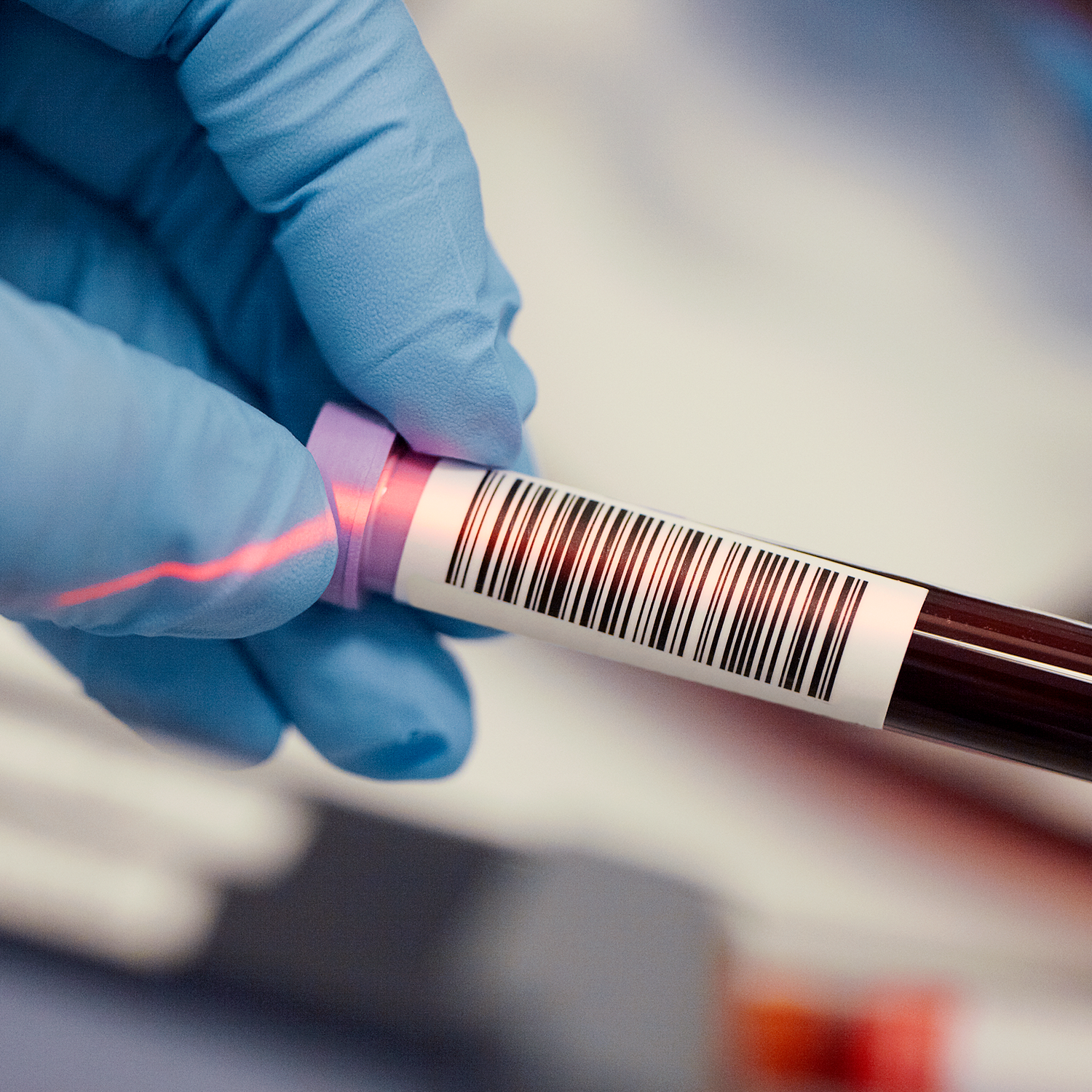 gloved hand holding vial of blood