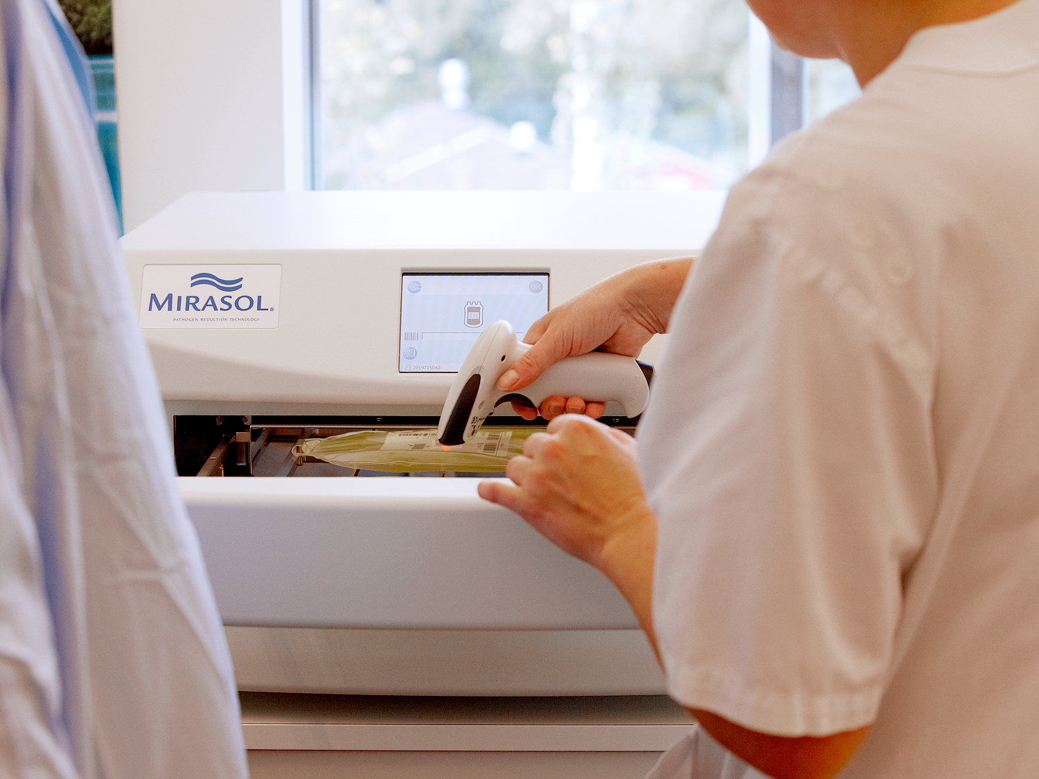 person scanning plasma bag on mirasol device