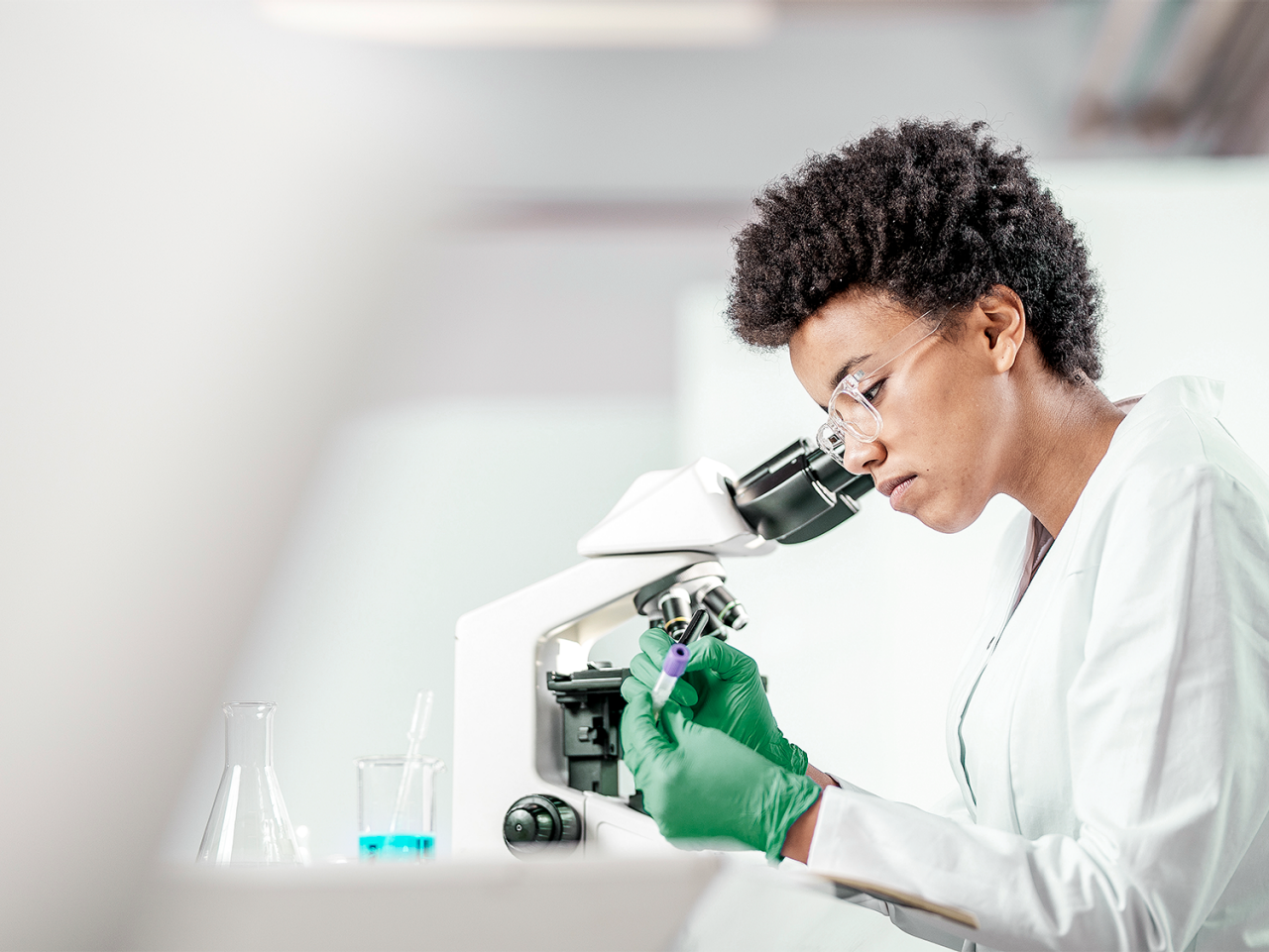 lab technician studying a sample with a microscope